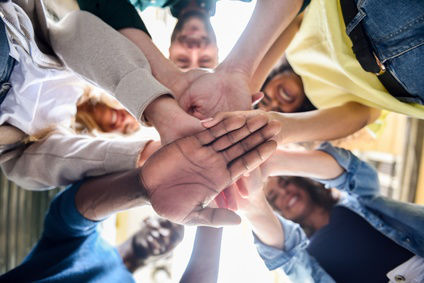 Young people putting their hands together.